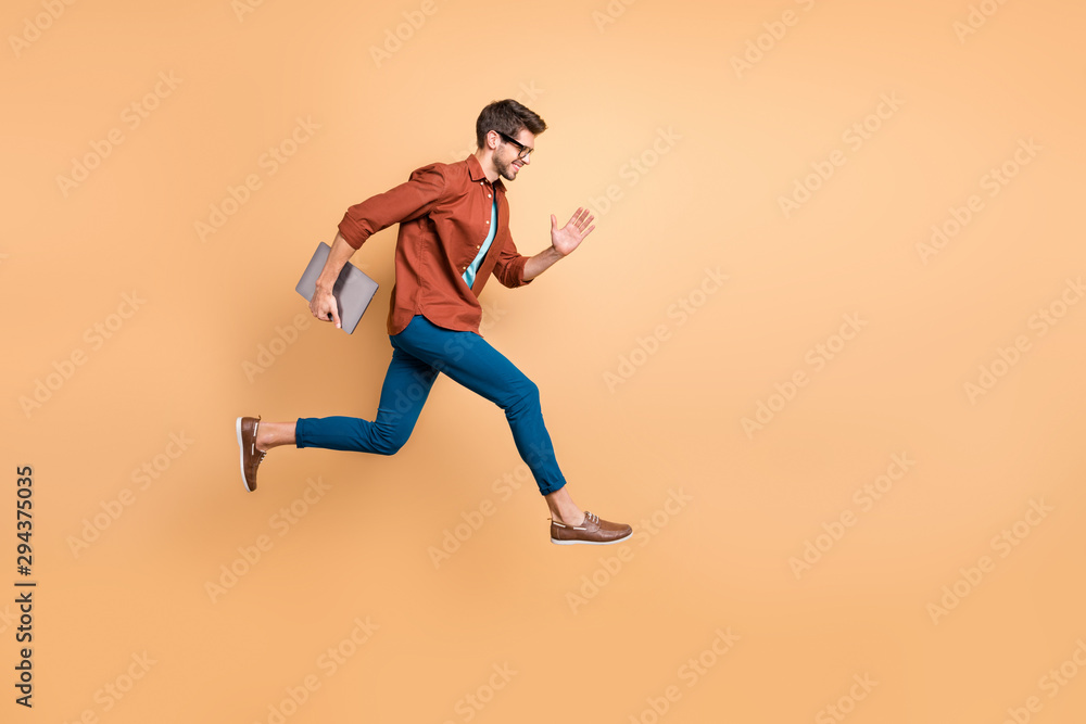 Full length body size view of his he nice attractive cheerful cheery successful brunet guy jumping in air carrying laptop running fast late hurry-up isolated over beige color pastel background
