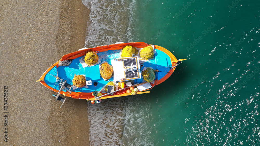 Aerial top view photo of red traditional wooden fishing boat in Aegean  island destination beach with emerald sea Stock Photo