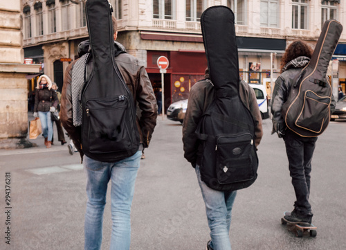 3 guitaristes marchent dans la rue d'une ville
