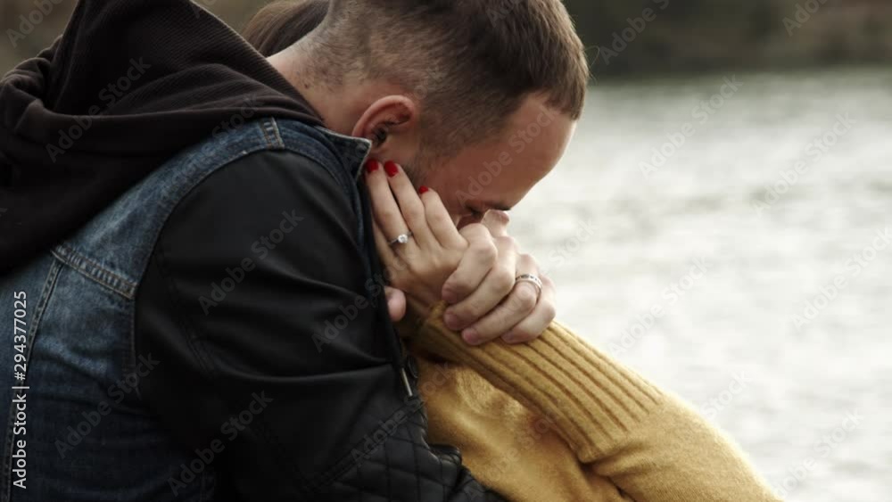 couple hugs in the park with river on the background. Autumn mood couple hugs in the park with river on the background. Autumn mood