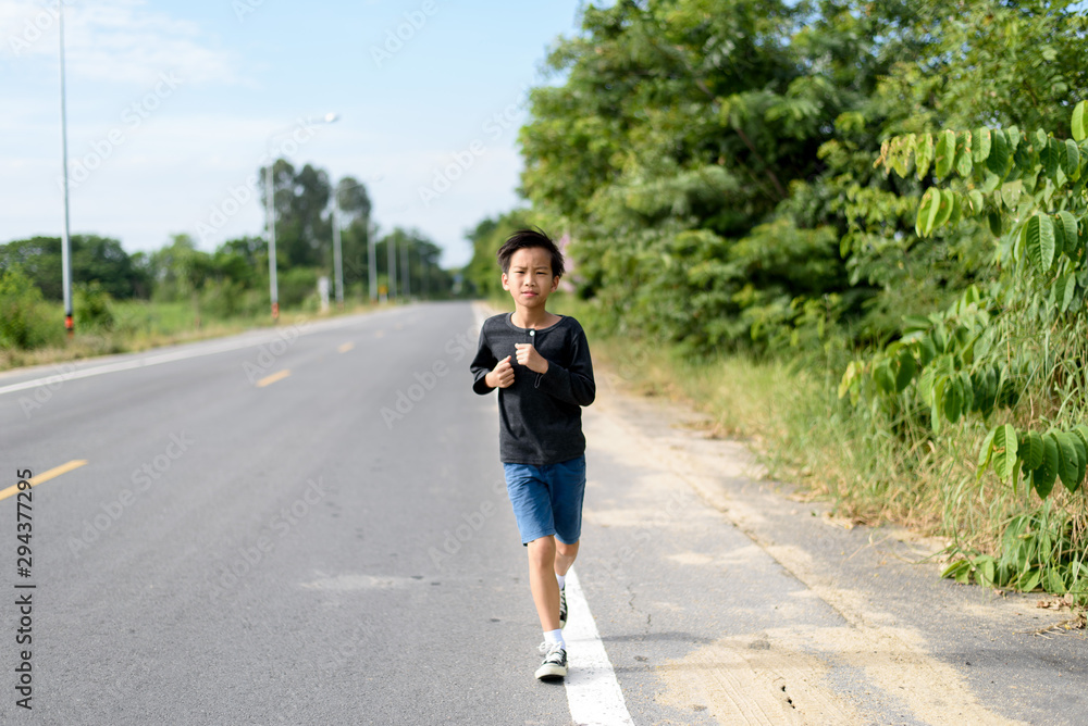 Young Asian boy running on a road
