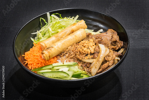 Rice noodles with grilled meat and spring roll, a popular Vietnamese cold rice vermicelli. Vietnamese cuisine.