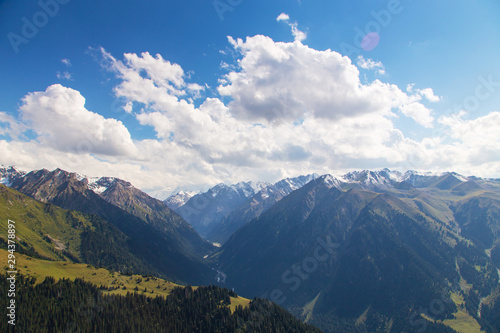 Mountain summer landscape. Snowy mountains and green grass. Peak Karakol Kyrgyzstan.