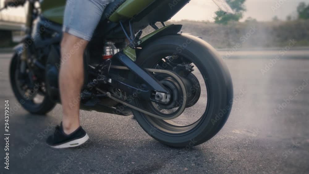 Motorcyclist doing tire burnout on a custom motorcycle, slow motion. Professional motorcyclist drift and turns on a motorcycle on the asphalt, a biker does a trick Motorcyclist doing tire burnout on a custom motorcycle, slow motion. Professional motorcyclist drift and turns on a motorcycle on the asphalt, a biker does a trick