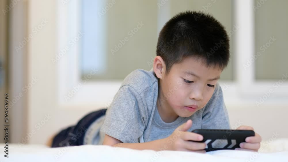 asian chinese boy playing smartphone on bed, kid use phone and play game, addicted game and cartoon, asian chinese boy playing smartphone on bed, kid use phone and play game, addicted game and cartoon,