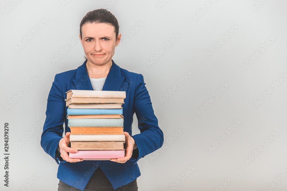 Young teacher carrying a stack of heavy books, frowning her face. Young teacher carrying a stack of heavy books, frowning her face.