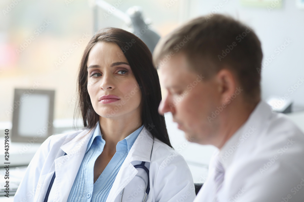 Woman dissatisfied doctor distrust looks at her colleague portrait. Incorrect treatment concept Woman dissatisfied doctor distrust looks at her colleague portrait. Incorrect treatment concept