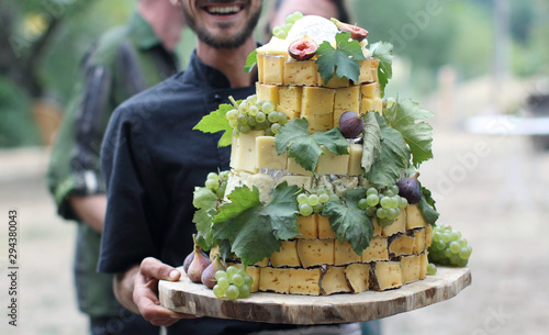 Non recognizable man holding cheese plate looking like a wedding cake in France
