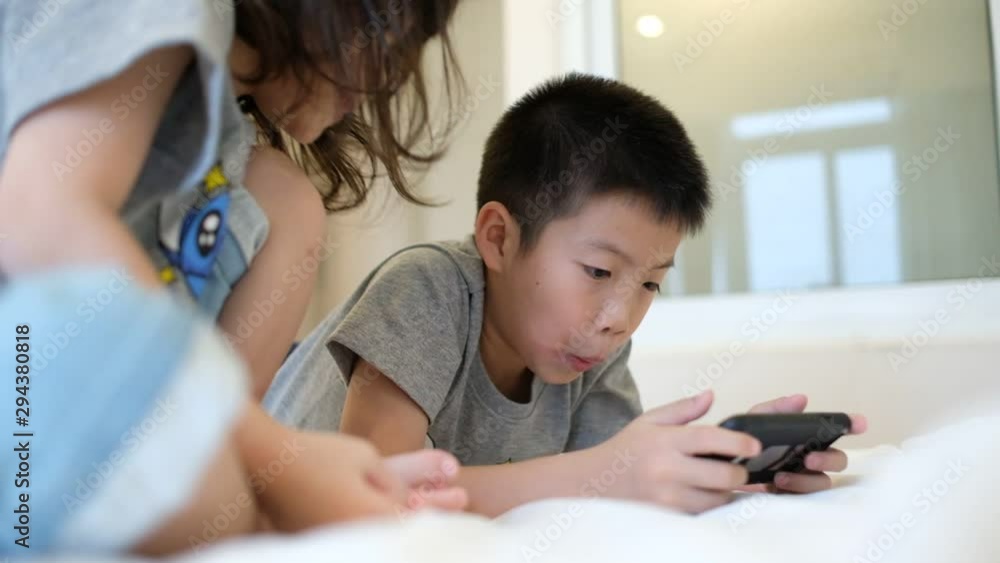 two chinese children addicted tablet, asian child watching tablet, kid use telephone together on their bed, play phone, kid addict smartphone two chinese children addicted tablet, asian child watching tablet, kid use telephone together on their bed, play phone, kid addict smartphone