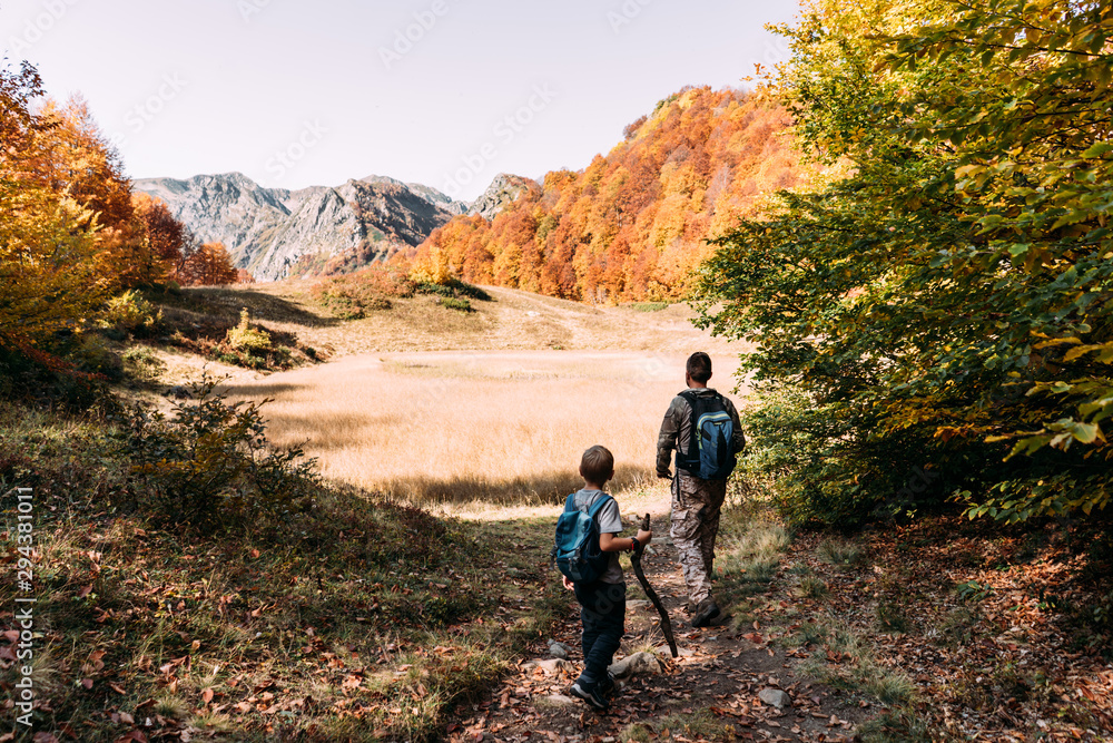 Dad and son walk along a mountain trail in the autumn. Fall mountain landscape.