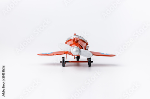 Miniature toy red retro airplane on white background. Metal model.