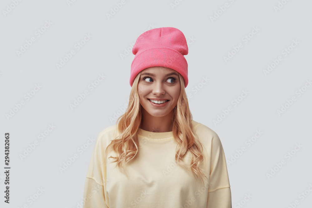 Attractive young woman looking away and smiling while standing against grey background Attractive young woman looking away and smiling while standing against grey background