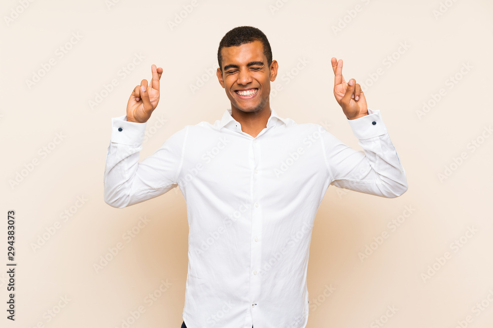 Young handsome brunette man over isolated background with fingers crossing