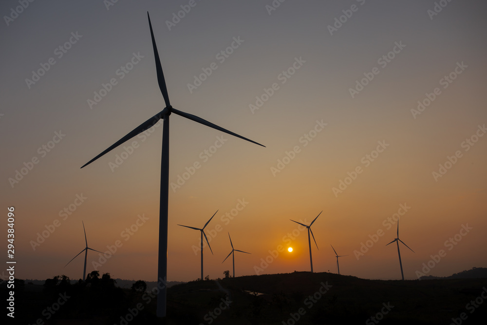 Wind turbines field new technology for clean energy on mountain at sunset.