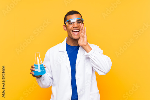 Scientific man holding a laboratory flask over isolated background shouting with mouth wide open