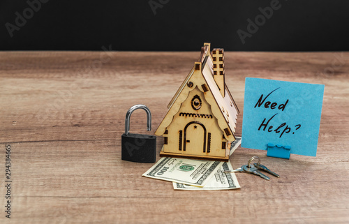 Wooden house with lock, dollar, and key on wood background