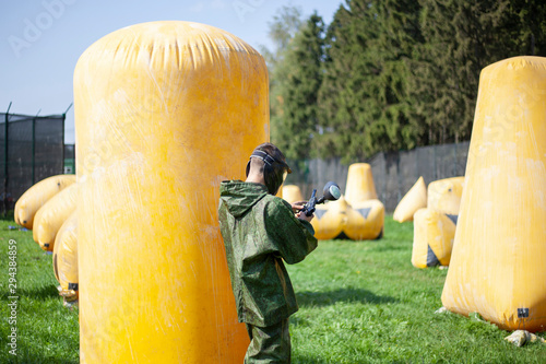 Paintball players on the training ground. The game of shooting paint. Playground with inflatable obstacles. Combat strategy in game military action.