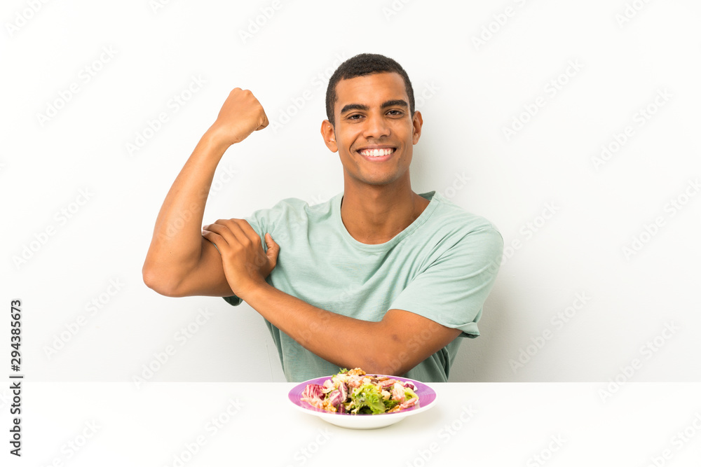 Young handsome man with salad in a table making strong gesture Young handsome man with salad in a table making strong gesture