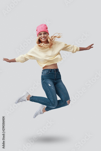 Bilde på lerret Full length of attractive young woman looking at camera and smiling while hoveri