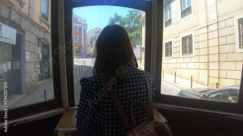 Young woman sitting in the back of the tram Lisbon streets buildings architecture window point of view