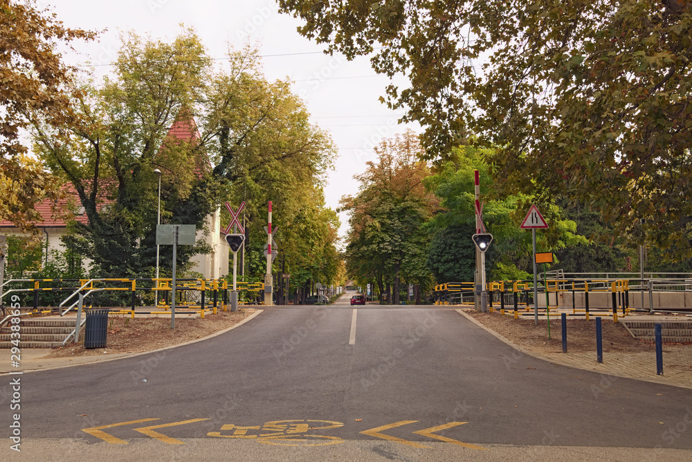 Railway crossing with barrier and light signal. Famous resort town Balatonfoldvar. Autumn landscape view. Famous touristic place and travel destination in Hungary Railway crossing with barrier and light signal. Famous resort town Balatonfoldvar. Autumn landscape view. Famous touristic place and travel destination in Hungary