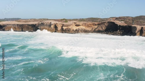 Ocean waves hitting the cliffs near Praia de Monte Clérigo in Portugal