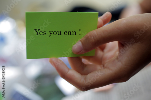 Hand with motivational notes on paper - Yes you can. Self reminder and words of wisdom concept.