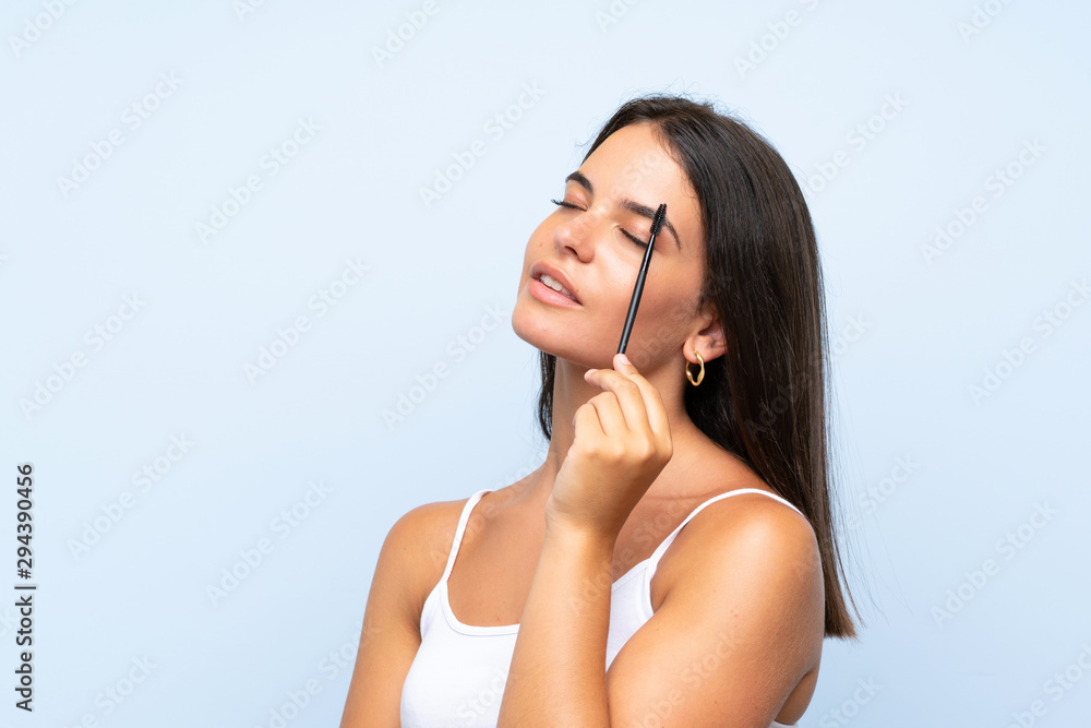 Young girl holding makeup brush over isolated background Young girl holding makeup brush over isolated background