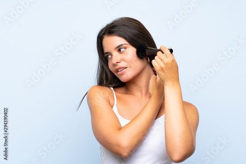 Young girl holding makeup brush over isolated background