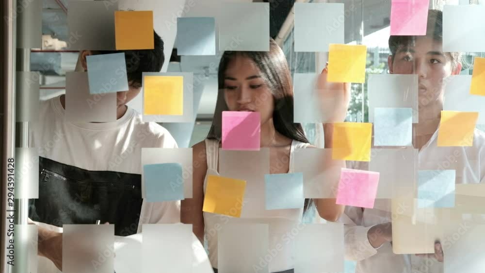 business people working planning discussing idea with sticky reminder note on glass wall
