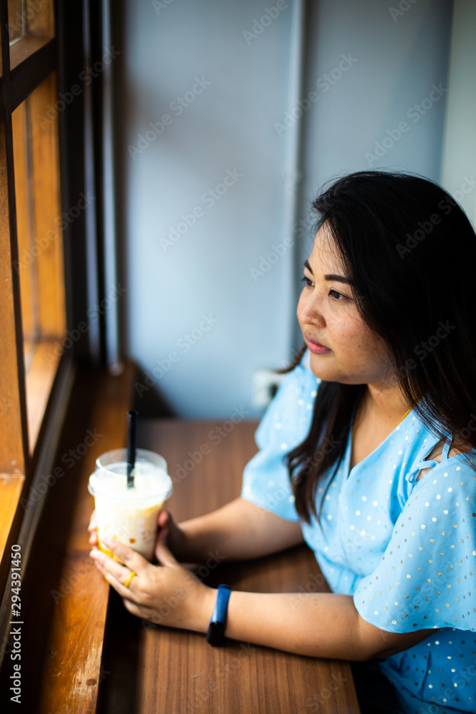 Cute overweight woman in coffee cafe, Happy Asian woman in a cafe with plastic cup coffee Cute overweight woman in coffee cafe, Happy Asian woman in a cafe with plastic cup coffee