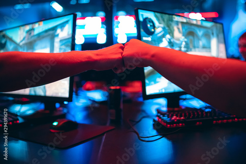 Obraz na plátně Professional gamer greeting and support team fists hands online game in neon color blur background