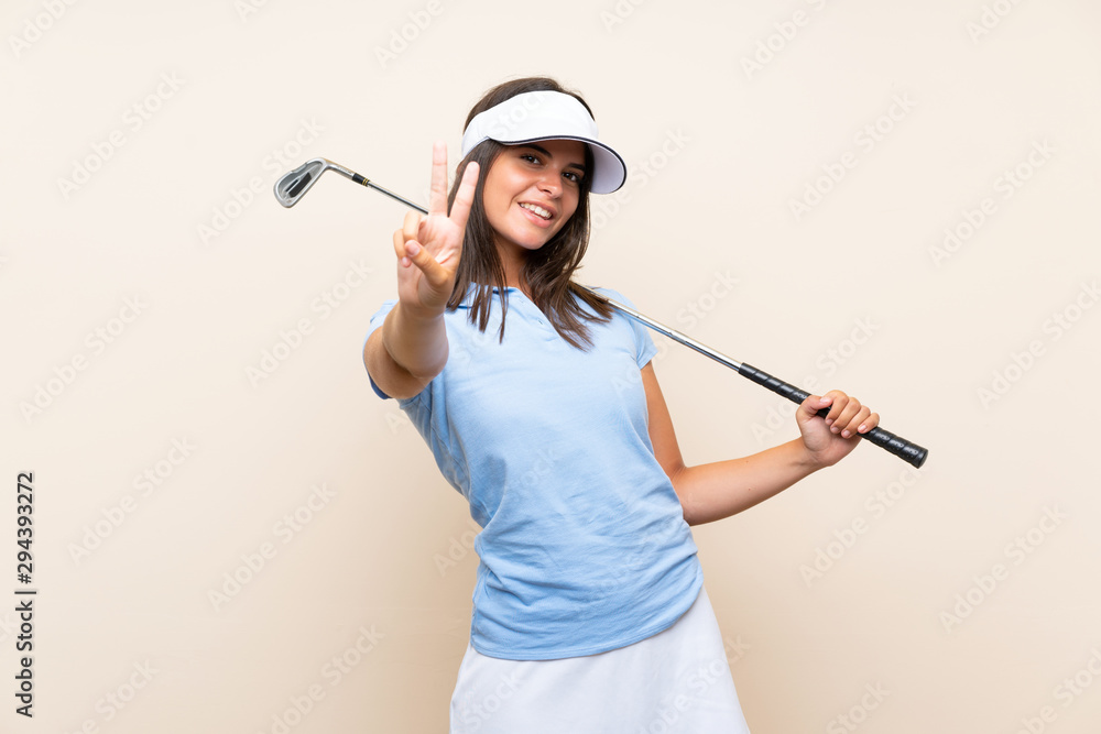 Young golfer woman over isolated background smiling and showing victory sign Young golfer woman over isolated background smiling and showing victory sign