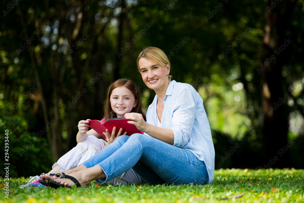 Mother and son are reading a book and smile at the park