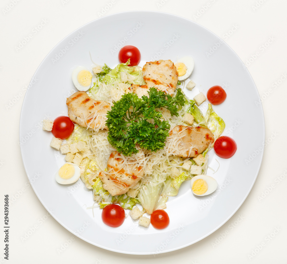 Caesar salad with chicken on a white plate and on a white background, top view. Caesar salad with chicken on a white plate and on a white background, top view.