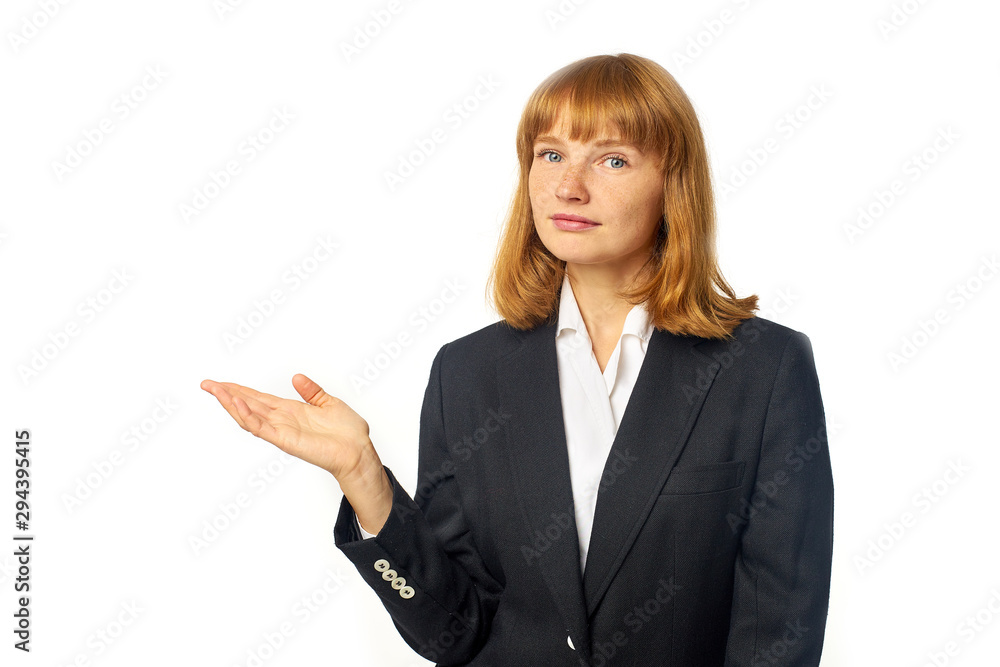 Image of young female office worker dressed in dark blazer and white shirt. Redheaded woman in business outfit showing with her hand to the copy space Image of young female office worker dressed in dark blazer and white shirt. Redheaded woman in business outfit showing with her hand to the copy space