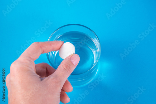 A hand holding effervescent soluble calcium tablet or vitamin C is placed in a glass of water. Health.The concept of a healthy lifestyle, prevention of vitamin deficiency. Isolated on white background