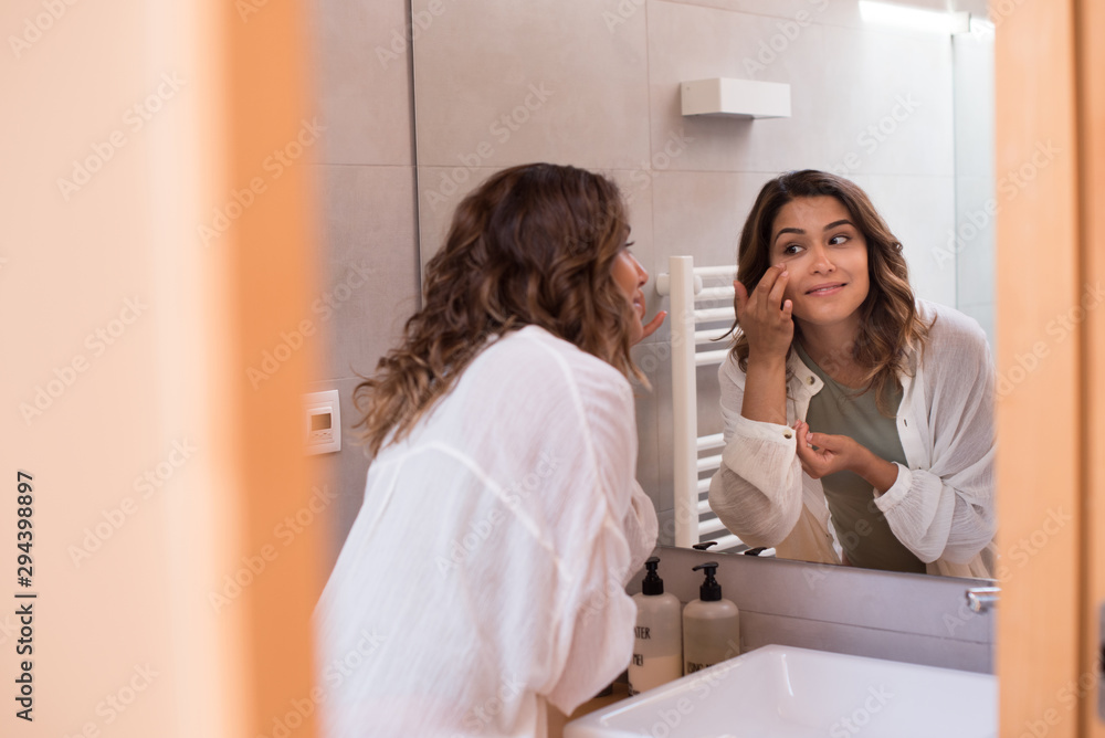 Beautiful woman in the bathroom moisturizing her skin Beautiful woman in the bathroom moisturizing her skin