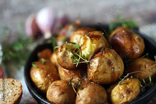 Rustic potato in a pan. Baked small potatoes in a peel with garlic and herbs. Selective focus. Macro.