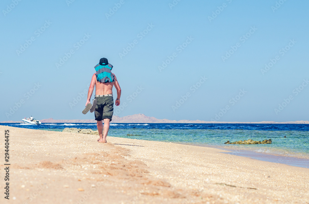 Barefoot man walks along the sandy sea coast Barefoot man walks along the sandy sea coast