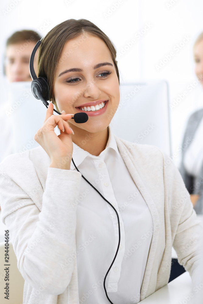 Call center. Group of operators at work. Focus on beautiful woman receptionist in headset at customer service white colored office. Business concept Call center. Group of operators at work. Focus on beautiful woman receptionist in headset at customer service white colored office. Business concept