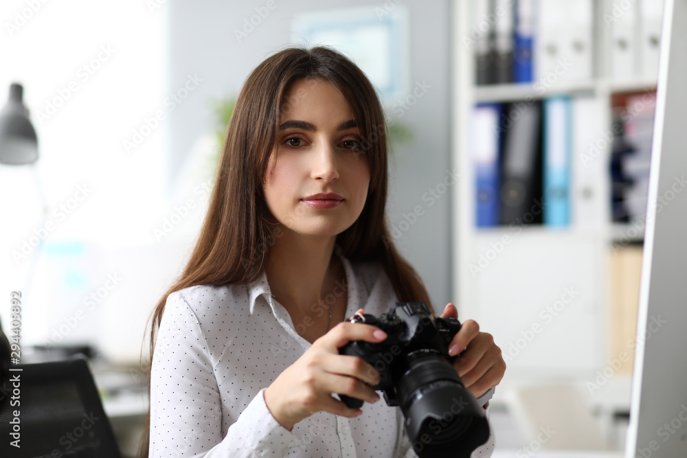 Woman sitting at worktable watching photosession at camera display headshot Woman sitting at worktable watching photosession at camera display headshot