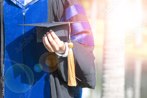 Doctor of Philosophy, PhD concept. Graduate student holding grad cap in gown suit finish from school in commencement ceremony. photo