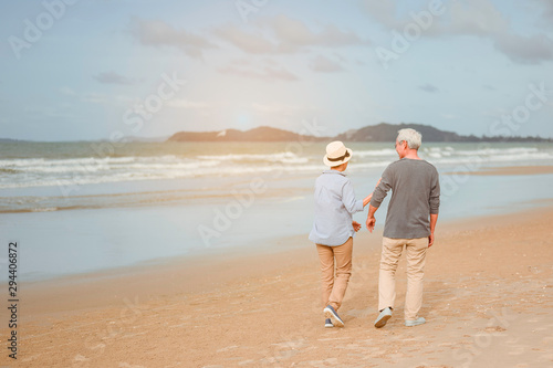 Senior couples walking on the beach, holding hands at sunset, planning a life insurance at retirement concept.
