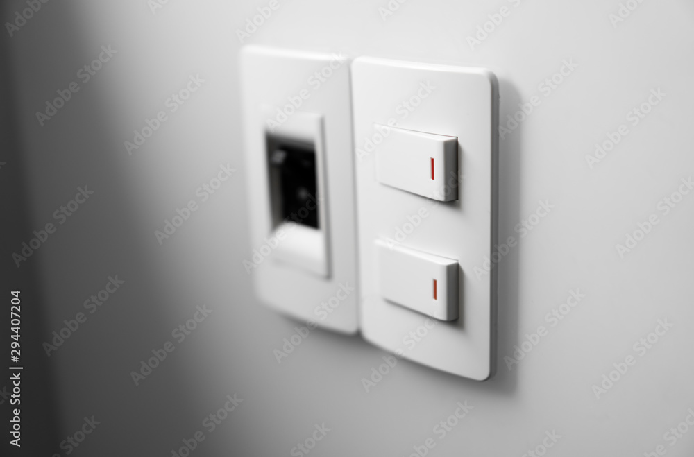 White switch on a white wall with two switches and one common switch. White switch on a white wall with two switches and one common switch.