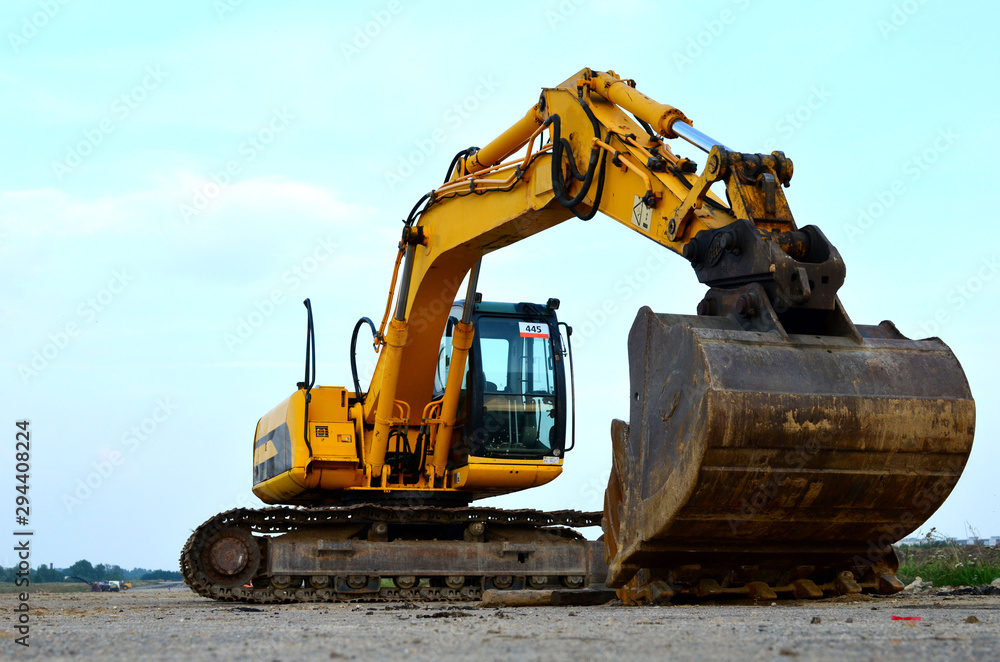 Large tracked excavator digs the ground for the foundation and construction of a new building in the city. Road repair, asphalt replacement, renovating a section of a highway, bridge construction Large tracked excavator digs the ground for the foundation and construction of a new building in the city. Road repair, asphalt replacement, renovating a section of a highway, bridge construction