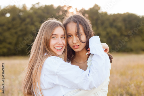 Two girls in white shirts hugging outdoors. Best friends
