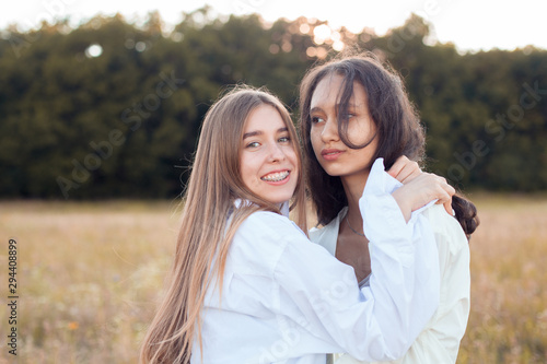 Two young women in white shirts hugging outdoors