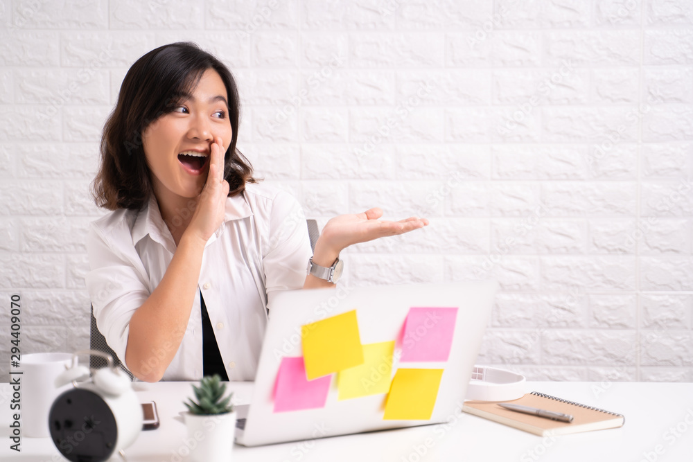 Woman sitting at home office using computer laptop and saying secret news Woman sitting at home office using computer laptop and saying secret news