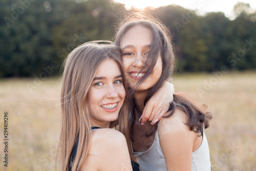 Two beautiful young women hugging outdoors at sunset. Best friends